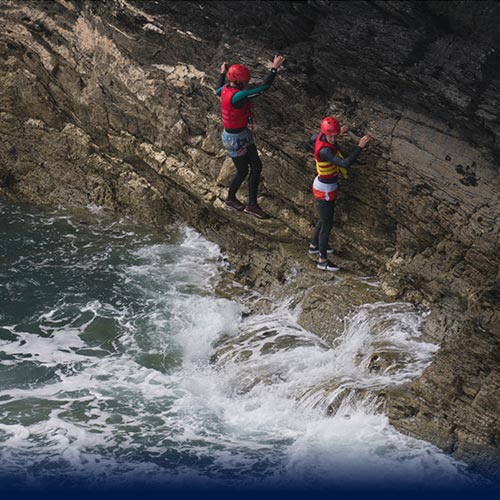 Two kid Coasteering on ledge avoiding water